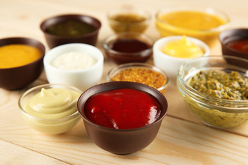 Bowls with different sauces on wooden table, closeup