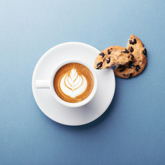 A cup of coffee and american cookies with chocolate chips on grey background. Top view.