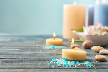 Candle with pebbles and sea salt for spa treatments on wooden table