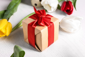 Gift box and beautiful flowers on light background