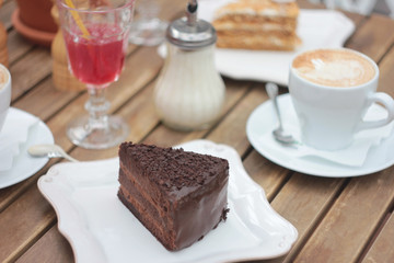 The piece of chocolate cake on table of summer terrace in cafe, picnic, set table