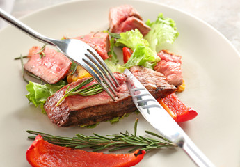 Cutting tasty meat on plate, closeup