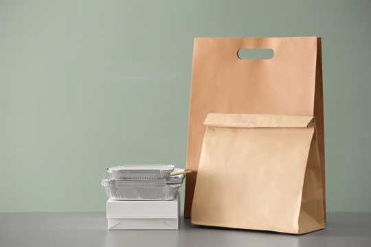 Different packages on table against color background. Food delivery service
