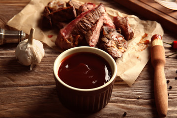 Bowl with barbecue sauce on wooden table