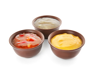 Bowls with different sauces on white background