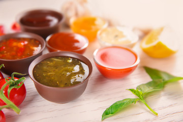 Bowls with different sauces and ingredients on light background