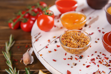 Bowls with different sauces on wooden board, closeup