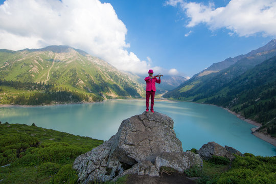 businessman in a red suit on top of a mountain in the background of a mountain lake,Big Almaty Lake