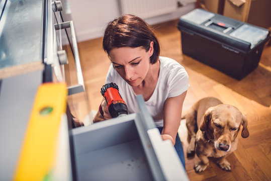 Woman with dog building kitchen and using a cordless drill