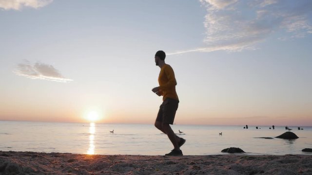 Young male runner training on the morning beach during sunrise