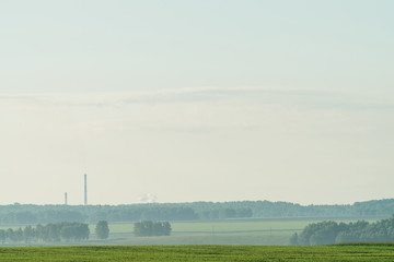 Misty fragment of plowed field in springtime. Rich green background of field with furrows from...