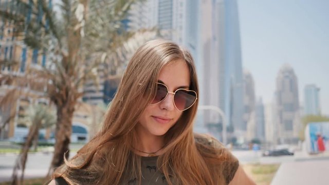 Girl in sunglasses on the background of Dubai streets and palms trees. Face close-up. Shooting in motion with collisions.