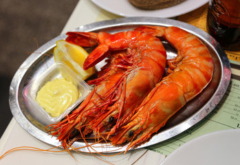 Jumbo shrimps with lemon and sauce on metal plate