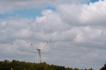 A large windmill on a background of blue sky with white clouds. Creating electricity through the wind. Renewable energy source.