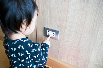 A child is trying to poke into electrical outlets. Kid with electrical socket.