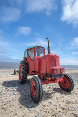 Quirky red diesel beach tractor. Vintage little red tractor