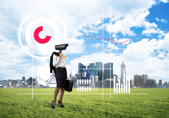 Camera headed woman standing on green grass against modern cityscape