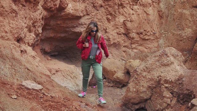 tourist is walking along the mountainous terrain. young woman traveler with backpack. red earth and mountains, like on Mars