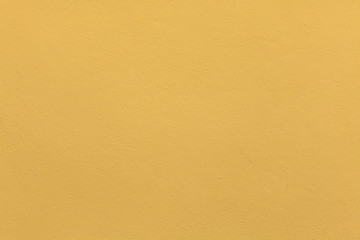 Yellow ochre painted stucco wall. Background texture