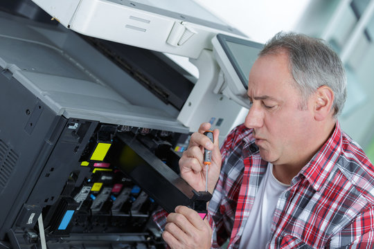 male senior technician is repairing a printer at office