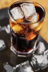 Cola with ice cubes and bubbles in glass.