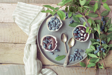 Honeysuckle berry and cup cakes with green leaves on a wooden table