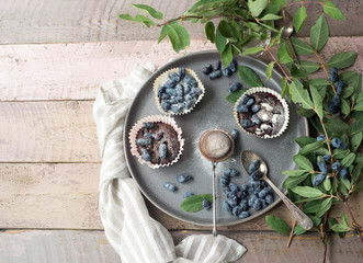 Honeysuckle berry and cup cakes with green leaves on a wooden table
