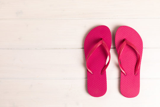 pink flip flops on white wooden background with copy space
