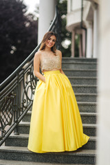 Lady in yellow erening dress stand on stairs