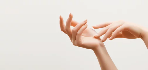 Afwasbaar Fotobehang Manicure Close-upbeeld van de handen van de mooie vrouw met lichtroze manicure op de nagels. Huidverzorging voor handen, manicure en schoonheidsbehandeling. Elegante en sierlijke handen met slanke sierlijke vingers