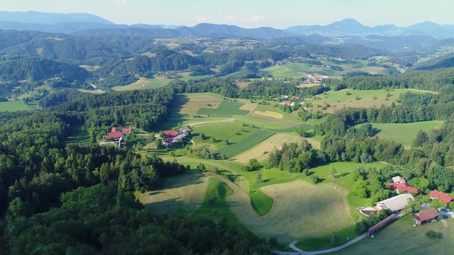 4k aerial wide shot of fields and farms between green hills