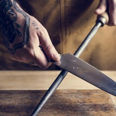 Professional chef sharpening knife in the kitchen