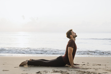 Fototapeta na wymiar Man practicing yoga on the beach
