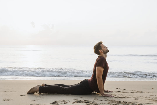 Man practicing yoga on the beach - Powered by Adobe