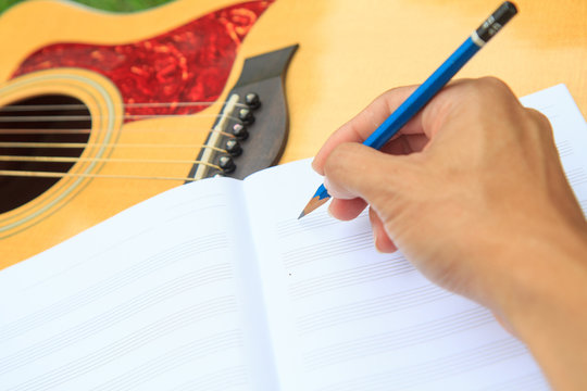 composer write note of song and use acoustic guitar for play