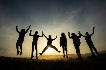 Fototapeta na wymiar Silhouette of children jumping, happy and fun in the morning grassland, sunrise in nature.