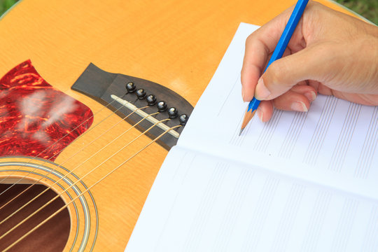 composer write note of song and use acoustic guitar for play