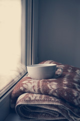 Details of still life in the home interior. Sweater, cup, wool, cozy, book, candle. Moody. Cosy autumn winter concept. Copy space