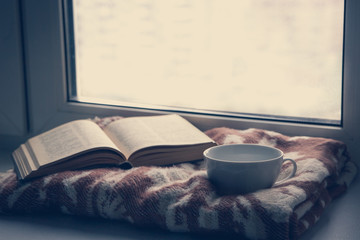 Details of still life in the home interior. Sweater, cup, wool, cozy, book, candle. Moody. Cosy autumn winter concept. Copy space