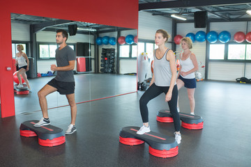 young sporty people training with steppers in gym