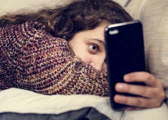 Teenage girl using a smartphone on a bed social media and addiction concept - obrazy, fototapety, plakaty