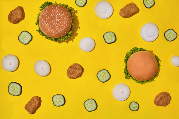 Most popular fast food meal. Chicken nuggets, burgers with fresh cucumber and onions on yellow background top view