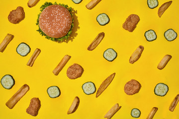 Most popular fast food meal. Chicken nuggets, burger and french fries on yellow background top view