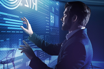 Smiling database administrator. Cheerful emotional database administrator feeling satisfied with the results of his work and smiling happily while touching the transparent screen