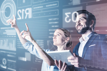 Smiling colleagues. Cheerful emotional skilled programmers smiling while standing in front of the screen and working at the new program