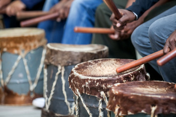 Drums being hit with sticks. The drum skins are made from cow hide.