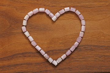 Pink heart on a wooden background. Kunzite is a natural pink stone for creating Jewelry. Natural...