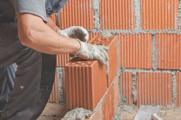 Real construction worker bricklaying the wall indoors.