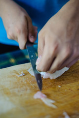 cook hands clean fish meat with knife on wooden chopping board