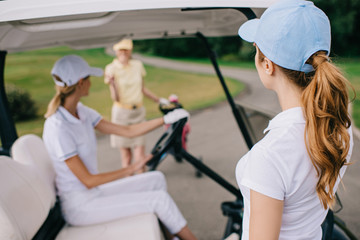 partial view of female golf players in caps at golf course